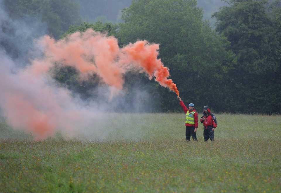 Mountain rescue men with a flare help guide a Coastguard helicopter to its landing site at Tafarn y Gerreg in Powys, Wales 