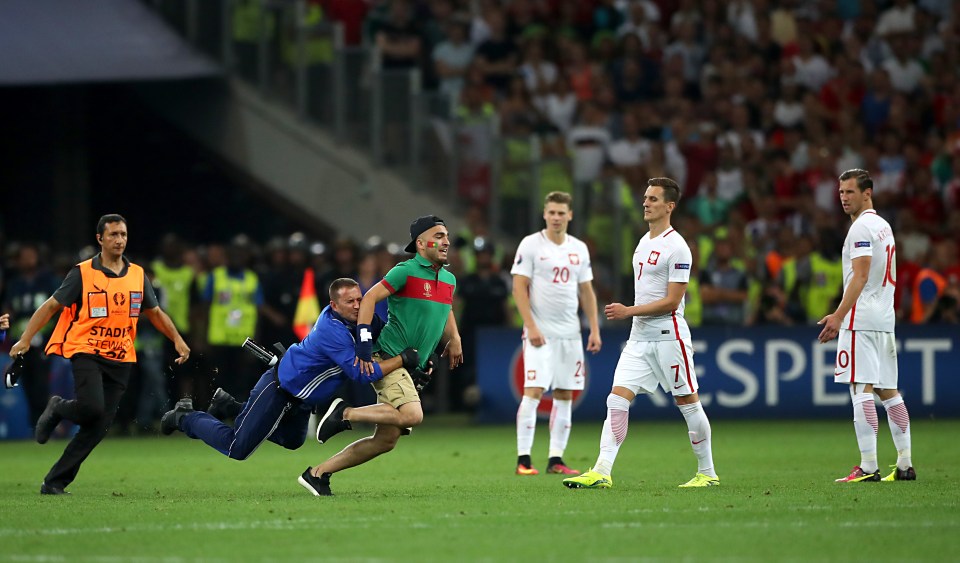 A supporter has to be tackled to the ground after running onto the pitch in Marseilles 