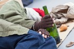 Homeless alcoholic with bottle of wine on a street