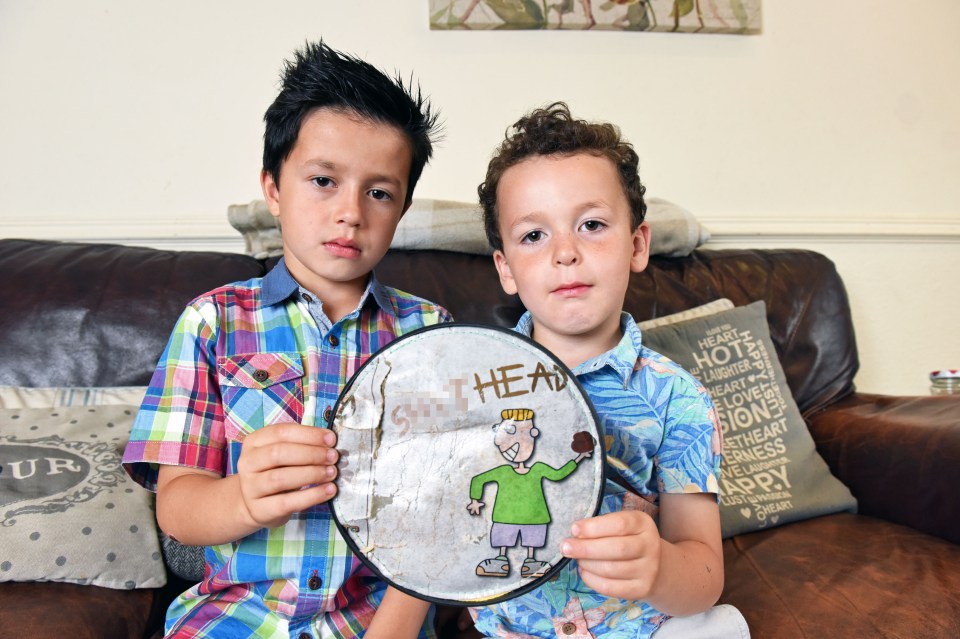 Louis and Theo, pictured with the child's toy which shows a boy about to throw a pile of poo, with the caption 'sh*thead'