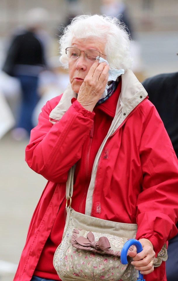 One woman pictured wiping tears from her eyes as she walks the streets of Batley town centre in tribute to Jo