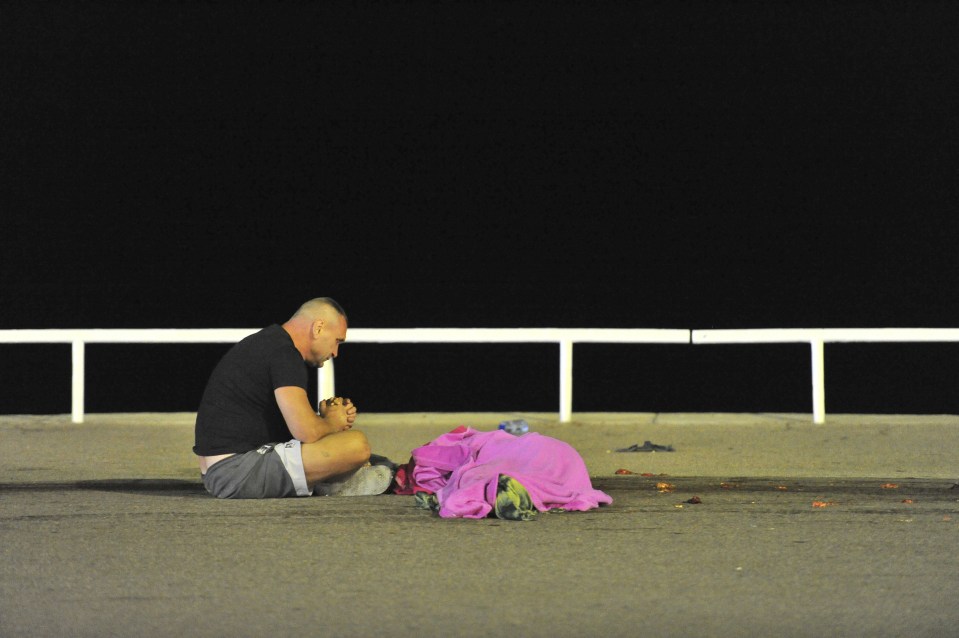 One distraught man sobs as he sits next to a body in the hours following the devastating attack. Hundreds were rushed to hospital following the murderous spree