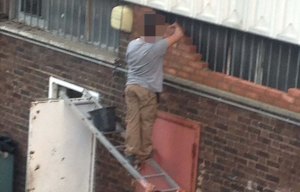 Builder stands on ladder balanced on open door directly in front of another that could open any second