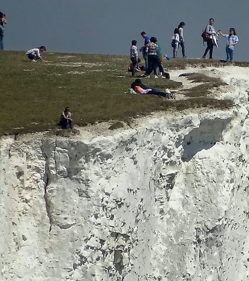 This shocking picture shows reckless sightseers at the edge of the Seven Sisters cliffs