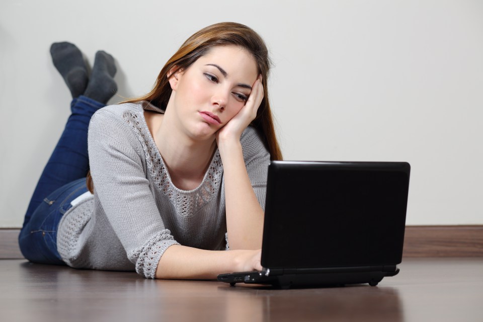 Bored teenager girl browsing social media in a laptop