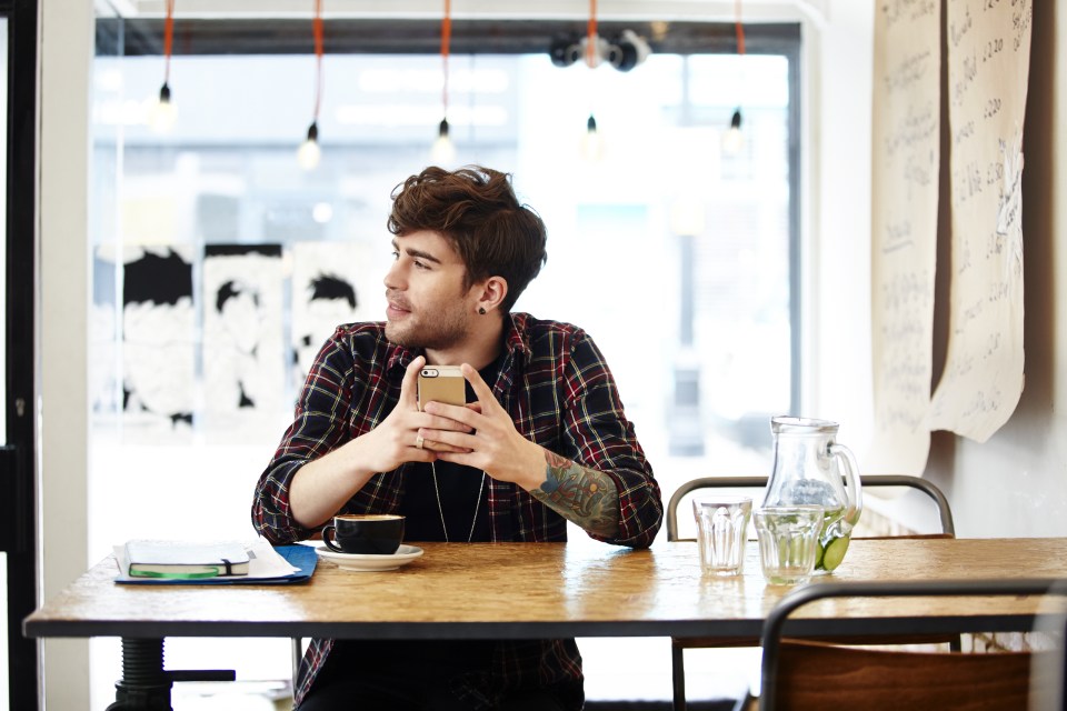 Guy with phone relaxing in coffee shop