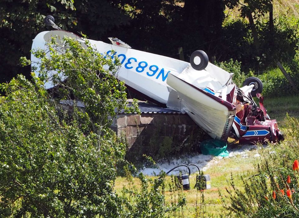 The crashed plane lies upside down on a brick building on a farm in Weymouth
