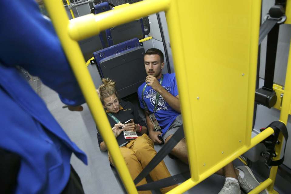 Media bus passengers lie on the floor after a window shattered in Rio de Janeiro