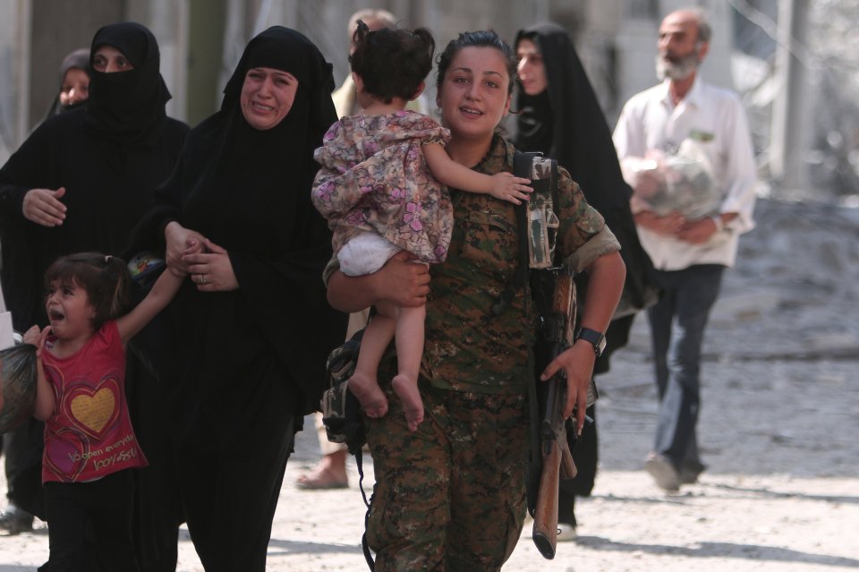 A Syria Democratic Forces (SDF) fighter helps civilians who were evacuated by the SDF from an Islamic State-controlled neighbourhood of Manbij