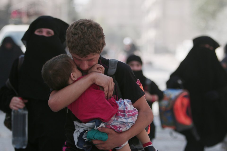 A civilian carries a child as he walks with others after they were evacuated by the Syria Democratic Forces (SDF) fighters from an Islamic State-controlled neighbourhood of Manbij