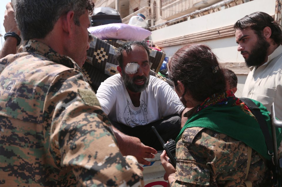 Syria Democratic Forces (SDF) fighters chat with an injured civilian who was evacuated with others by the SDF from an Islamic State-controlled neighbourhood of Manbij