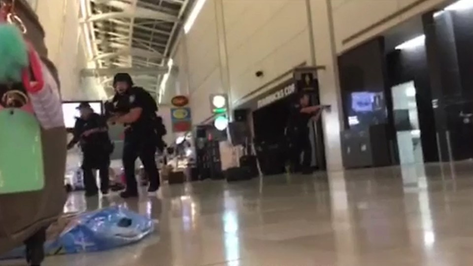 An armed cop charges through the airport during the terror scare