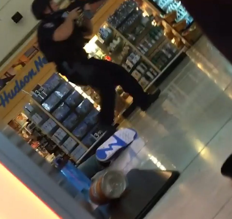 A police officer is seen making his way through the airport while passengers hide