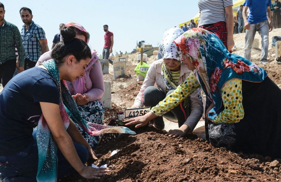 Women gesture as they kneel by a grave in Turkey during the funeral