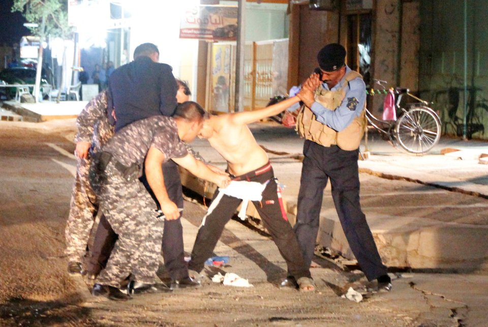 Iraqi security forces remove a suicide vest from a boy in Kirkuk