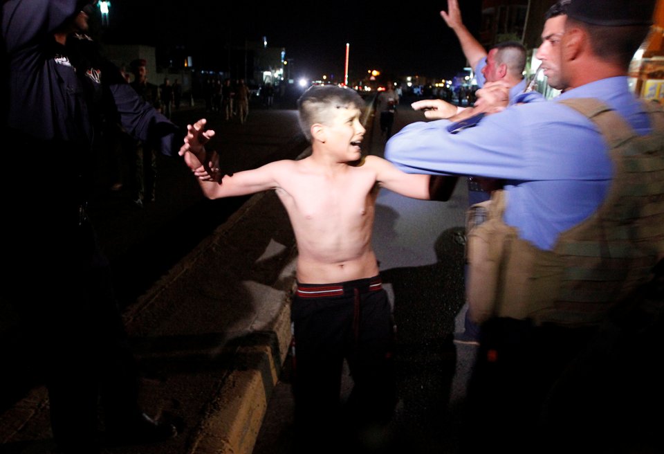Iraqi security forces detain a boy after removing a suicide vest from him in Kirkuk