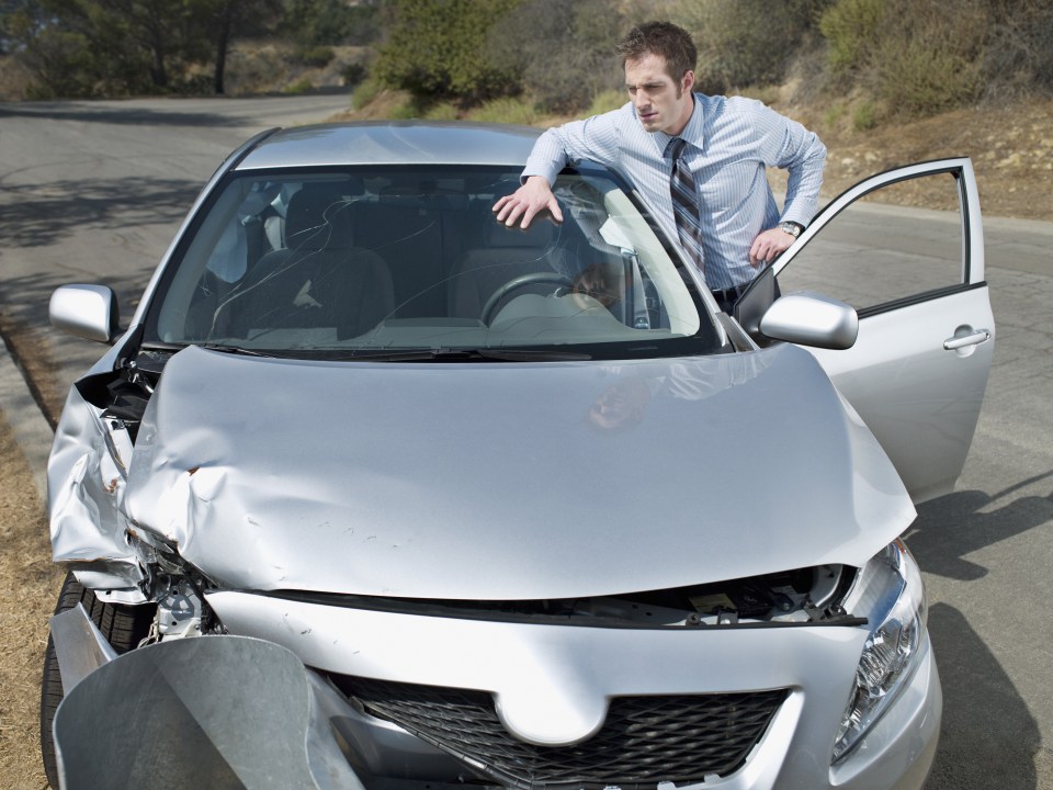 Businessman looking at car accident damage