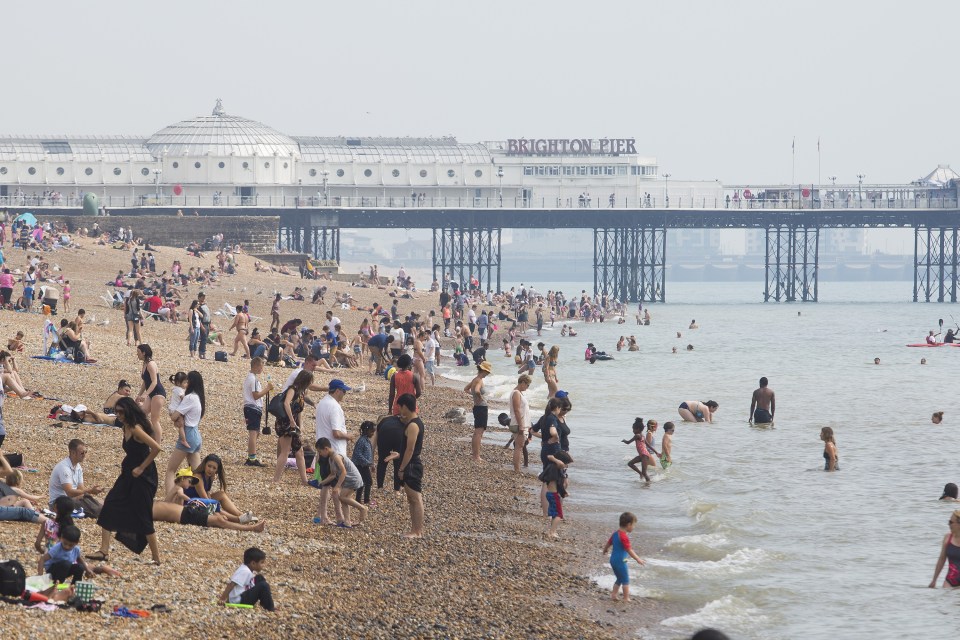 Members of the public take advantage of warm and humid weather to cool down in the sea and relax on the beach in Brighton