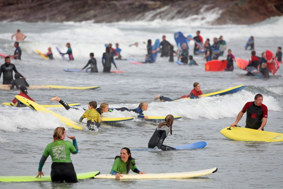 Bodyboarders and surfers fill the sea at Polzeath in Cornwall