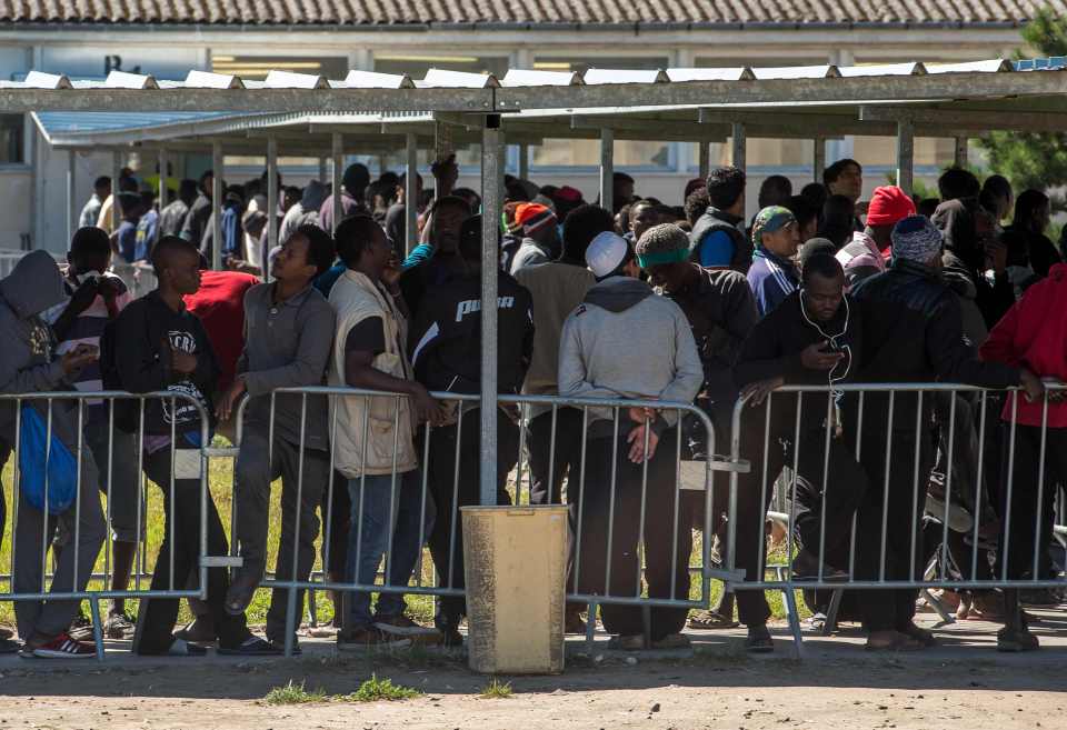 Migrants queue to receive food distributed by charities