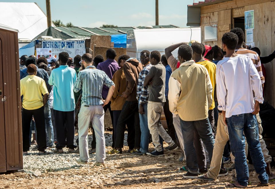 Migrants queue at a distribution point inside the 'Jungle' camp for migrants and refugees in Calais