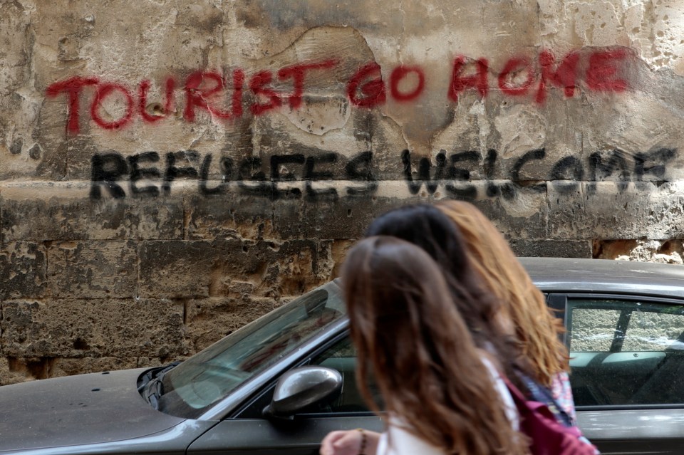 People walk past a graffiti in Palma de Mallorca