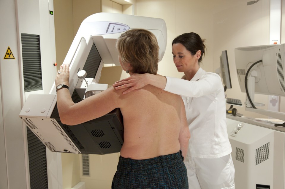 Mature woman having breast exam using mammography machine