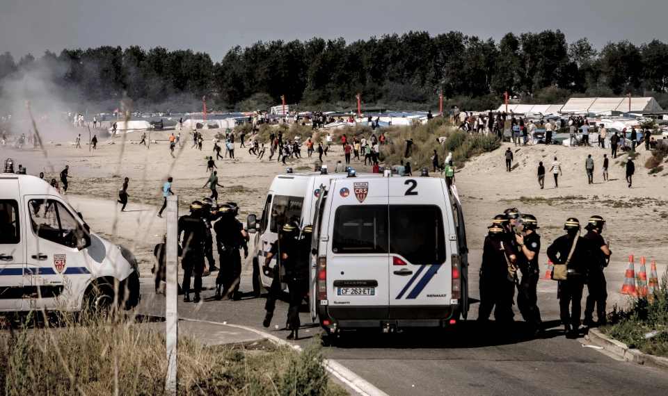 Riot police disperse migrants on the beach in Calais