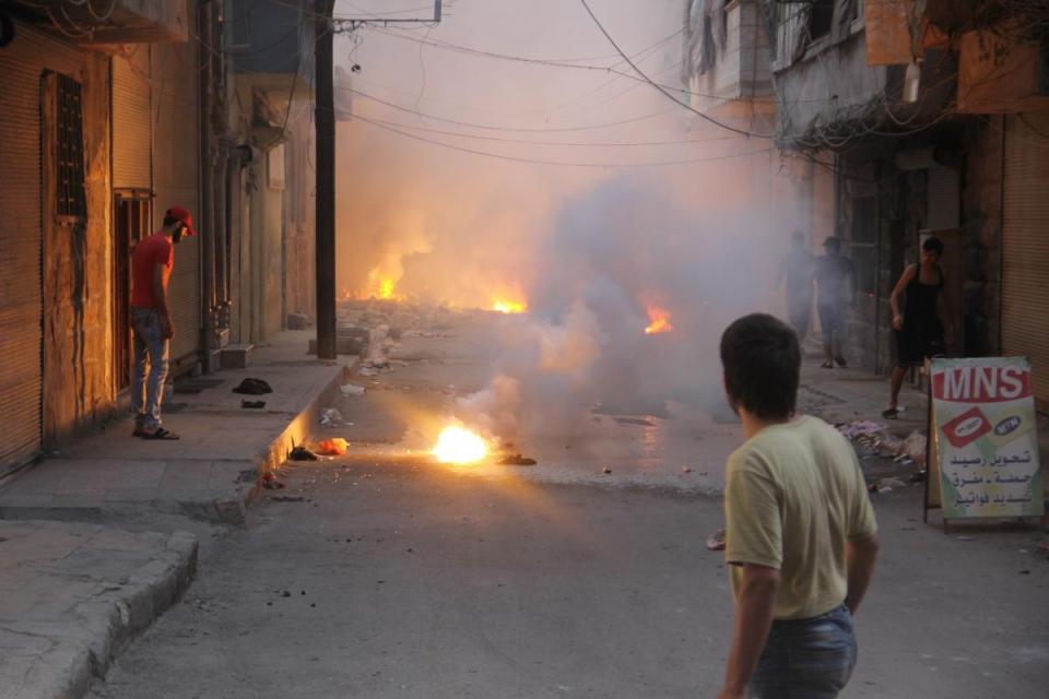 At least four incendiary submunitions burn on the ground of a narrow street in the al-Mashhad neighborhood of opposition-held east Aleppo