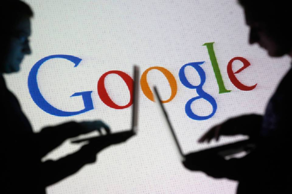 People pose with laptops in front of projection of Google logo in this picture illustration taken in Zenica