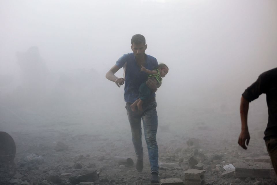 TOPSHOT - A Syrian man carrying a child