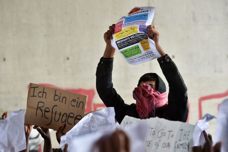 Demonstrator hold up placards reading 'I am a refugee' and 'Migrants welcome' 