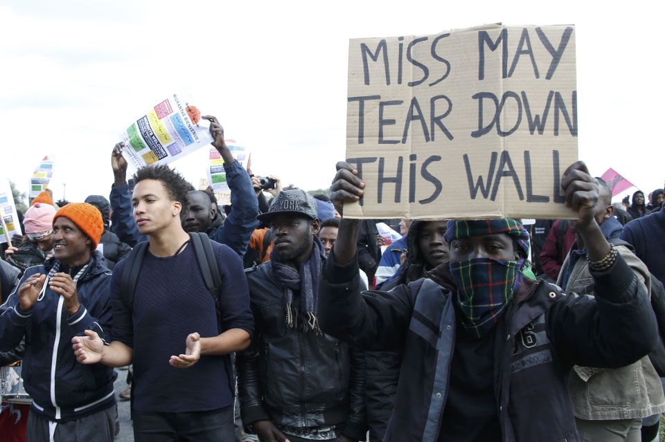 A migrant holds up a placard reading 'I am a refugee' and 'Migrants welcome' 