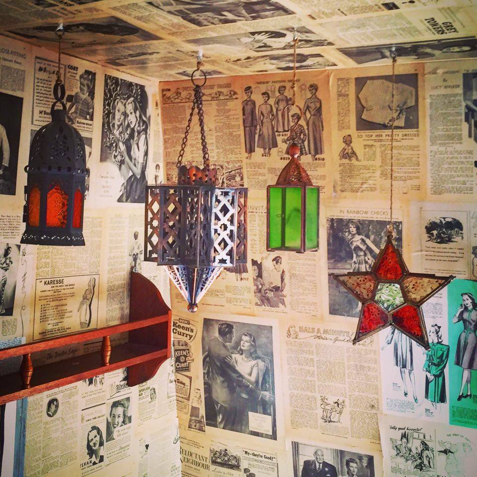 Pretty lanterns hang from the walls, which are papered in vintage magazine pages
