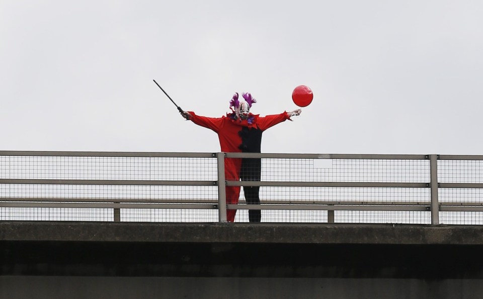 FAMEFLYNET - Exclusive: The Killer Clown Craze Shows No Sign Of Slowing Down As An Individual Dressed As A Clown Brandishing A Sword Is Seen On A Bridge Taunting Traffic Below On The M20