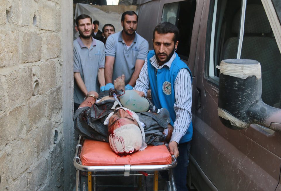 A wounded man is stretched away from the bombing zone