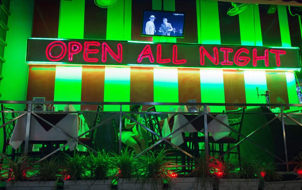 A woman sits alone in a restaurant bar near Soi Cowboy in Bangkok early on October 1