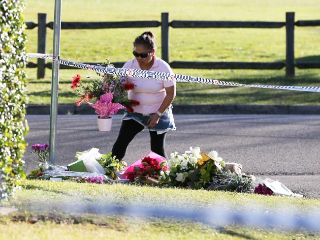A woman places flowers outside the family murder crime scene in Davidson