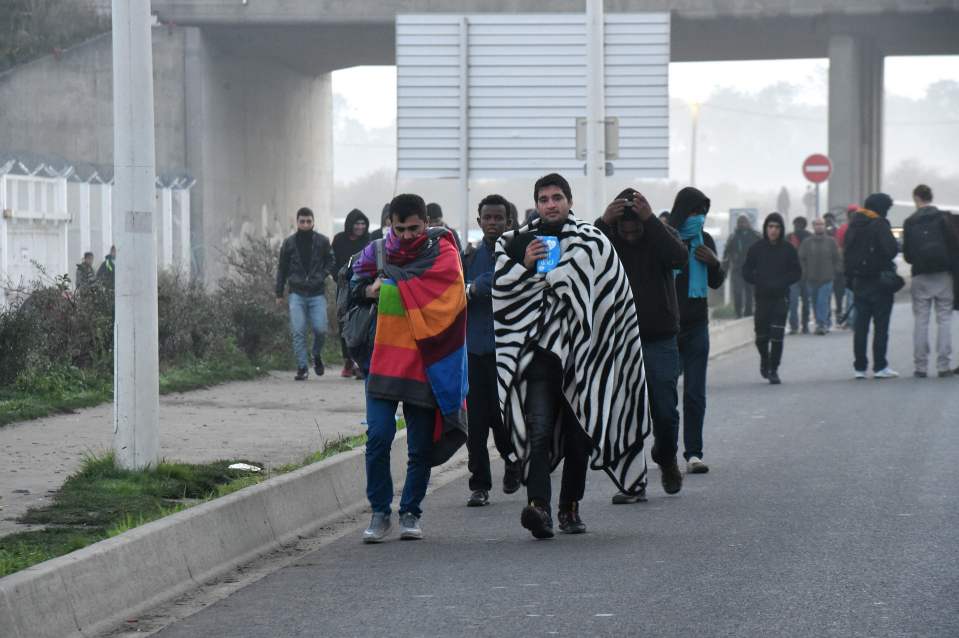 Migrants walk on a road during the full evacuation of the Calais "Jungle" camp