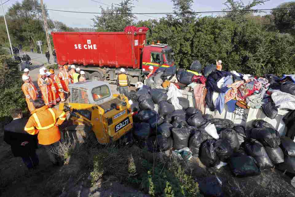 Workmen collect rubbish as they start to dismantle makeshift shelters on the second day the evacuation of migrants and their transfer to reception centers in France, as part of the dismantlement of the camp called the "Jungle" in Calais