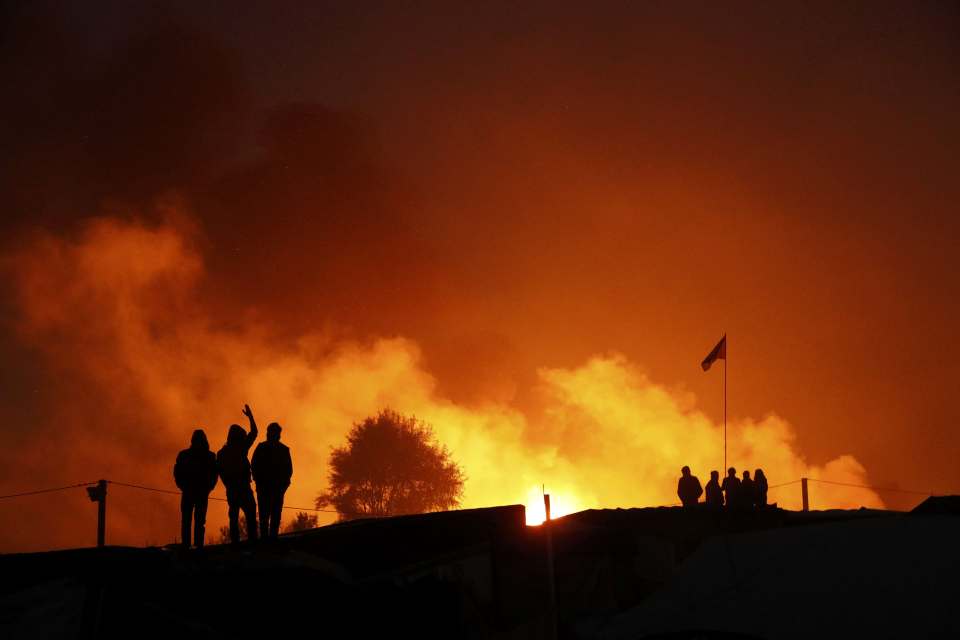 Calais burning... Migrants are silhouetted by a blaze