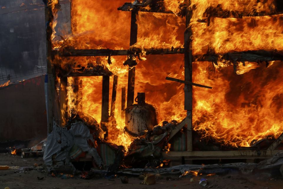  A gas bottle is seen among the flames from a makeshift shelter in the "Jungle"