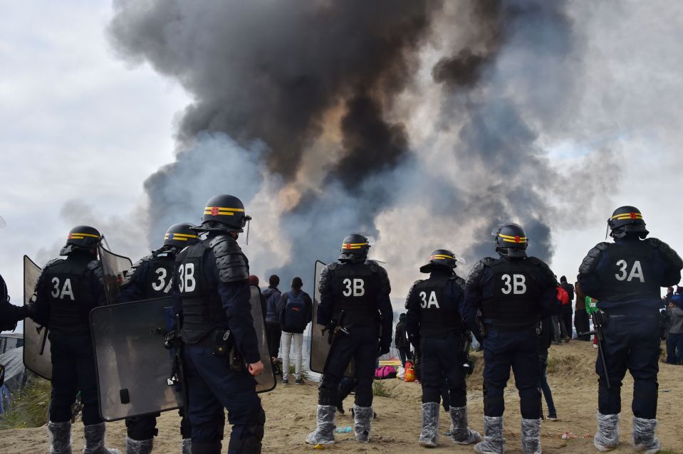 Migrants have been bused out of the camp after French police moved in to clear it this week. Fired raged after some buildings were set alight