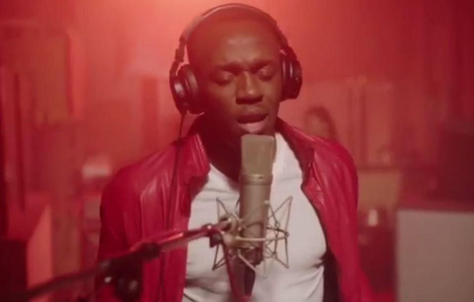 The Jamaican sprint king wore a stylish red jacket and white tee for the cheesy clip