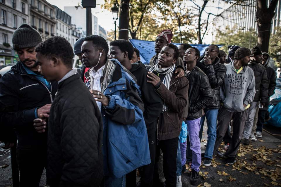Migrants queue as soap is distributed in a street in Paris