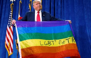 Trump looks awkward holding up LGBT flag given to him by fan as support in community slips to 12 per cent