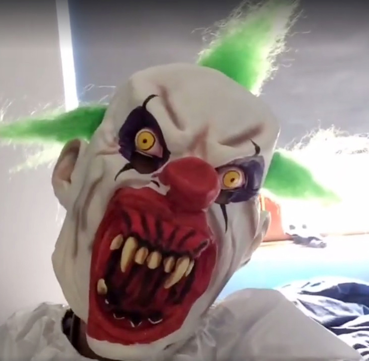 The first person in Britain to be fined - and get a criminal record - for dressing as a killer clown was today unmasked as a jobless teenager. Connor Jones, 18, terrified children at a school by dressing as a clown in a black and white jumpsuit with snarling scary mask and green hair. Jones was arrested for breaching public order at the school - and fined ¿90 for his clown scare. Police were called after reports of a mystery man dressed in a clowns outfit "intimidating" children outside St Cenydd Comprehensive School in Caerphilly, South Wales. Jones was visited by officers at his nearby home - and admitted he had stood on a pedestrian bridge outside the school and neighbouring Hendre Infants school as children were leaving on Friday. Pictured here is Connor Jones dressed as a clown WALES NEWS SERVICE