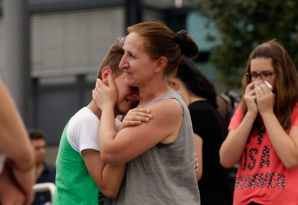 People mourn near the crime scene outside the OEZ shopping centre the day after a shooting spree left nine victims dead on July 23