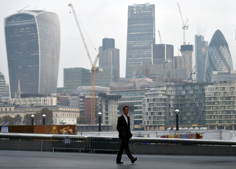 A man walks in front of the City of London financial district of London, Britain 
