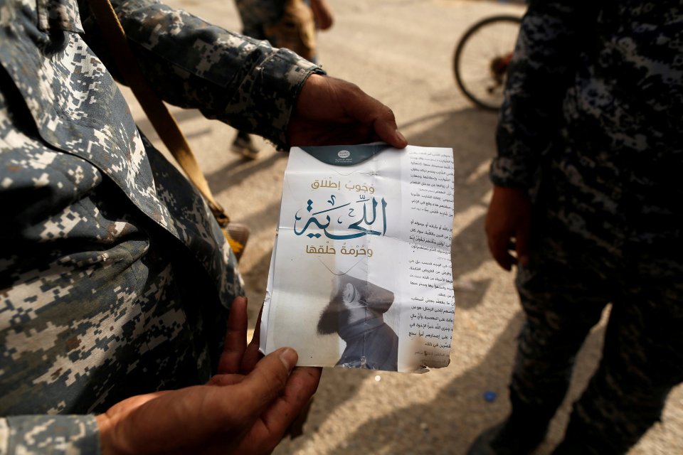 An Iraqi soldier shows a pamphlet which reads "Wearing beards is compulsory, shaving is prohibited"
